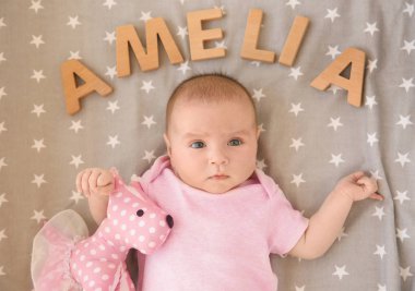 Şirin bebek oyuncak ve word Amelia ile yatakta yatarken ahşap harflerden oluşur. İsim kavram seçme