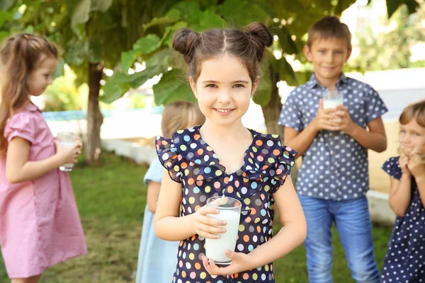 Portrait of little girl with glass of milk in green park — Stock Photo, Image