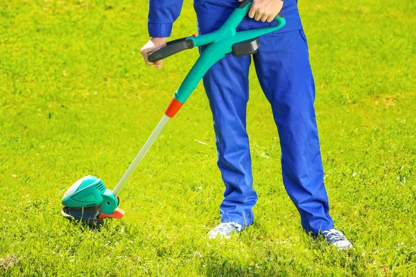 Worker mowing lawn with grass trimmer — Stock Photo, Image