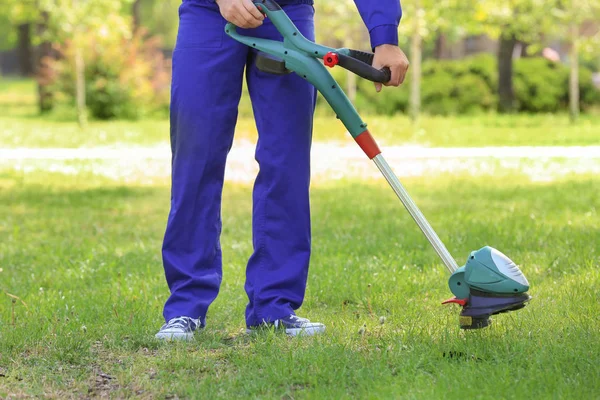 Worker mowing lawn with grass trimmer — Stock Photo, Image