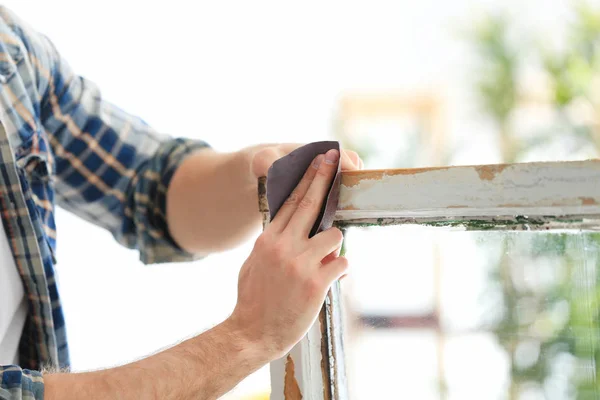 Arbeiter schleift Oberfläche des alten Fensterrahmens — Stockfoto