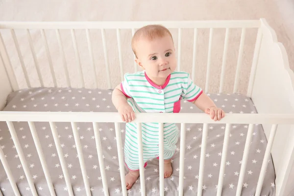 小さな赤ちゃんのベビーベッドに立っています。 — ストック写真