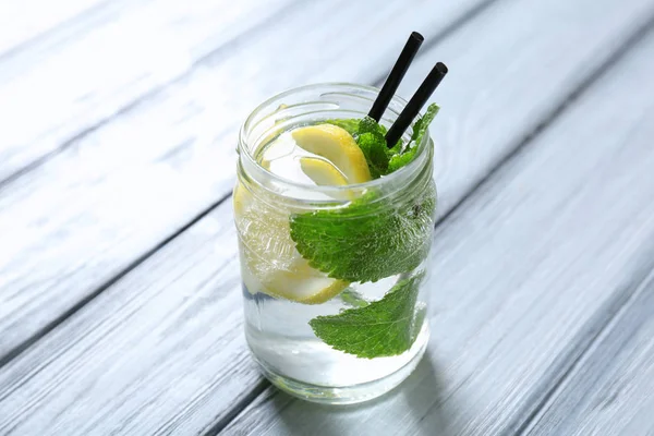 Glazen pot met koud citroen water en rietjes — Stockfoto