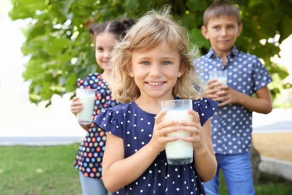 Porträtt av liten flicka med glas mjölk i grön park — Stockfoto