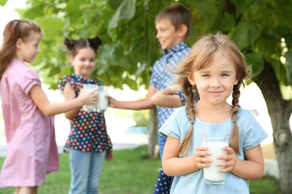 Pohár tej zöld parkban kislány portréja — Stock Fotó