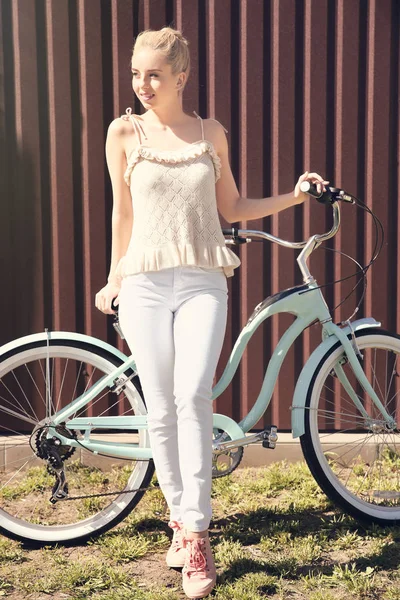 Leende kvinna med cykel nära färg vägg — Stockfoto