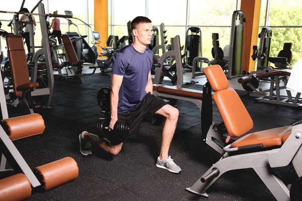 Sporty young man training legs in gym — Stock Photo, Image