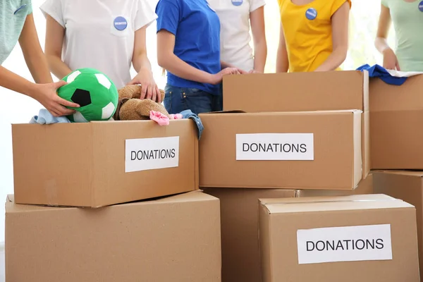 Jóvenes voluntarios con cajas de donaciones en interiores —  Fotos de Stock