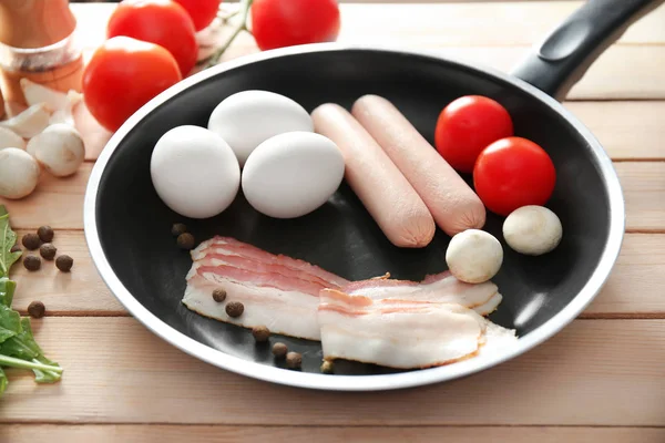 Ahşap masa üzerinde tavada yumurta ile lezzetli breakfast için ham maddeler — Stok fotoğraf