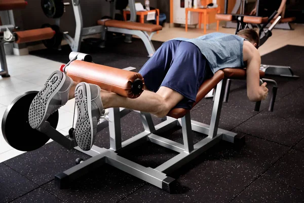 Deportivo joven entrenamiento piernas en el gimnasio — Foto de Stock