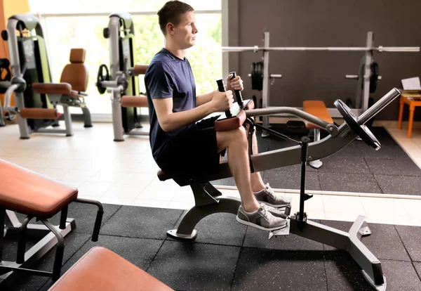 Sporty young man training legs in gym — Stock Photo, Image