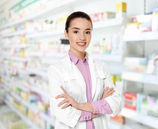 Młoda kobieta farmaceuty w pracy. Niewyraźne półki z produktów farmaceutycznych na tle — Zdjęcie stockowe