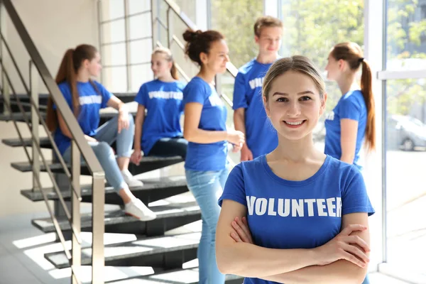 Young girl with her team near staircase indoors. Volunteering concept — Stock Photo, Image