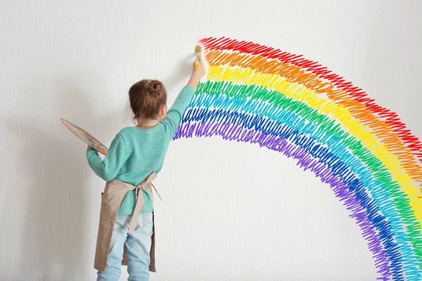 Έννοια της παιδικής ηλικίας. Μικρή ζωγράφος σχέδιο ουράνιο τόξο σε φόντο λευκό τοίχο — Φωτογραφία Αρχείου