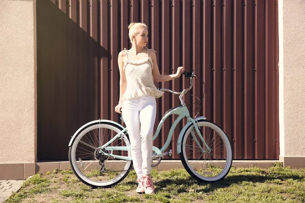 Молодая улыбающаяся женщина с велосипедом возле цветной стены — стоковое фото