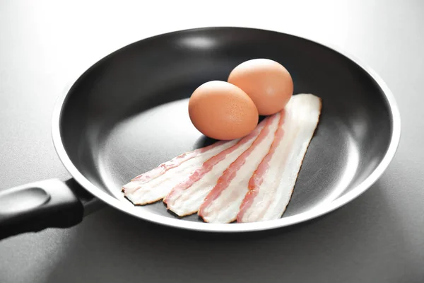 Обсмажування сковороди з сирими яйцями і беконом на столі — стокове фото