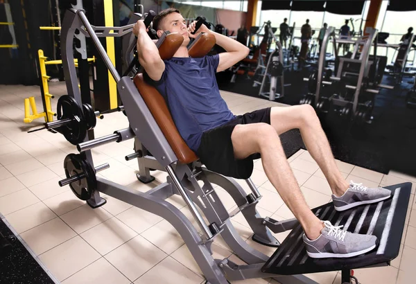 Sporty young man training legs in gym — Stock Photo, Image