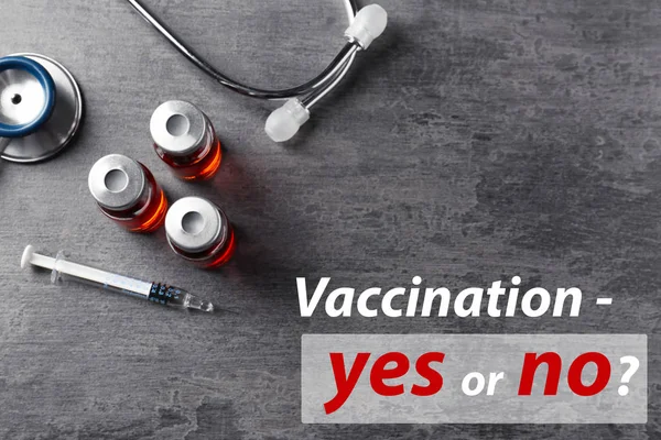 Vaccination debate concept. Vials and syringe with vaccine on gray background — Stock Photo, Image