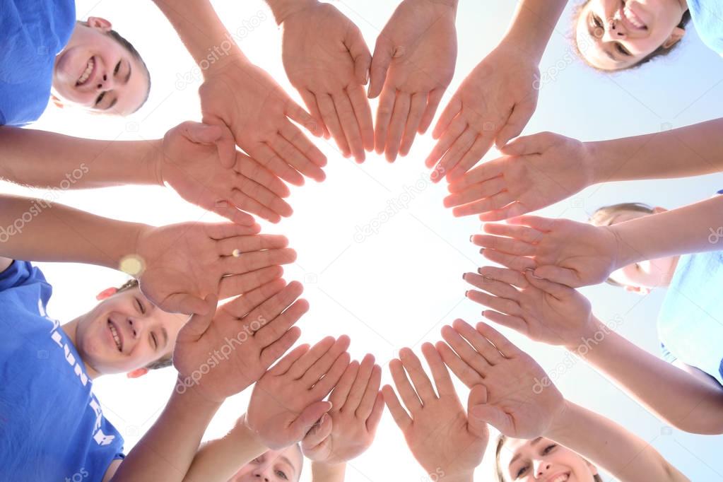 Team of volunteers putting their hands together as symbol of unity, bottom view