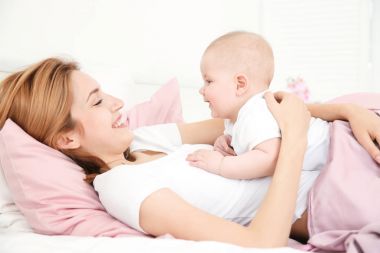 Mutlu genç kadınla evde yatakta yatarken şirin bebek