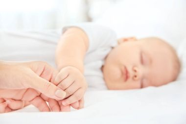 Sevimli uyuyan bebek, closeup elini tutan genç kadın