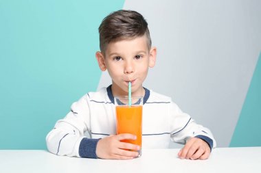 Sevimli küçük çocuk renk arka plan üzerinde masada otururken suyu içme