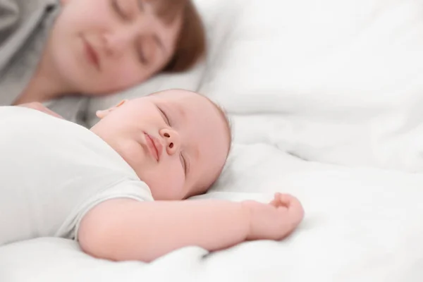 Lindo bebé con madre durmiendo en la cama en casa, primer plano —  Fotos de Stock
