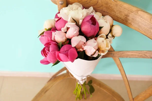 Boeket van mooie pioenroos bloemen op stoel in de buurt van kleur muur, close-up — Stockfoto