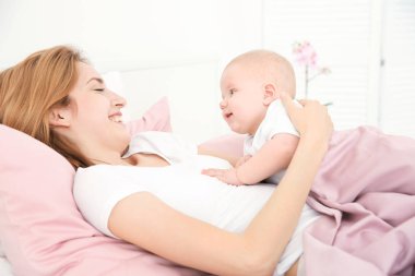 Mutlu genç kadınla evde yatakta yatarken şirin bebek