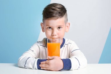 Sevimli küçük çocuk bardak renkli arka plan üzerinde masada oturan suyu ile