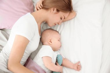 Genç kızla yatakta evde uyuyan sevimli bebek