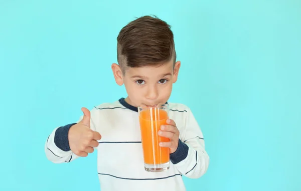 可爱的小男孩，在彩色背景上喝果汁 — 图库照片