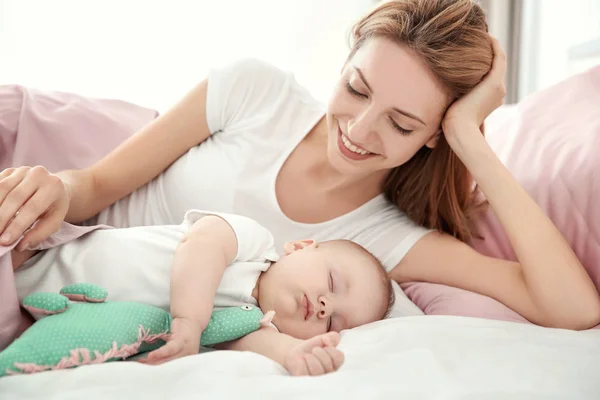 Wanita muda dengan bayi tidur yang lucu berbaring di tempat tidur di rumah — Stok Foto