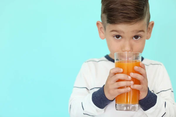可爱的小男孩，在彩色背景上喝果汁 — 图库照片