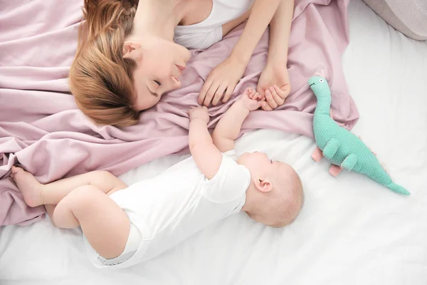 Wanita muda dengan bayi lucu tidur di tempat tidur di rumah — Stok Foto