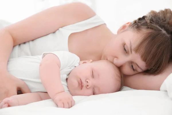 Mujer joven con lindo bebé durmiendo acostado en la cama en casa —  Fotos de Stock