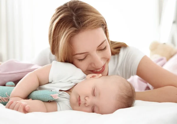 Wanita muda dengan bayi tidur yang lucu berbaring di tempat tidur di rumah — Stok Foto