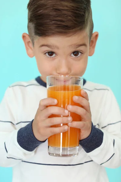 Söt liten pojke dricka saft på färg bakgrunden, närbild — Stockfoto