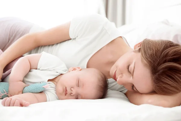 Wanita muda dengan bayi lucu tidur di tempat tidur di rumah — Stok Foto