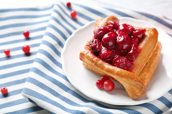 Plate with puff and cherry on striped napkin — Stock Photo, Image