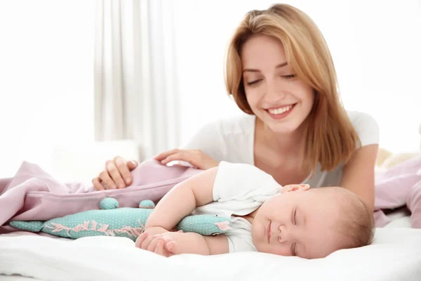 Jovem mulher com bebê adormecido bonito deitado na cama em casa — Fotografia de Stock