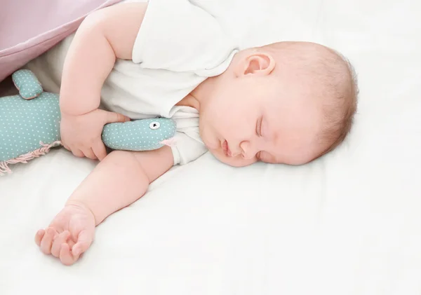 Χαριτωμένο μικρό μωρό με το παιχνίδι στον ύπνο στο κρεβάτι στο σπίτι — Φωτογραφία Αρχείου