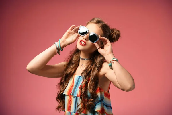 Красива стильна жінка з сонцезахисними окулярами на кольоровому фоні — стокове фото