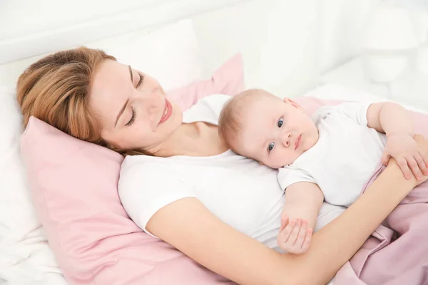 Wanita muda bahagia dengan bayi lucu berbaring di tempat tidur di rumah — Stok Foto