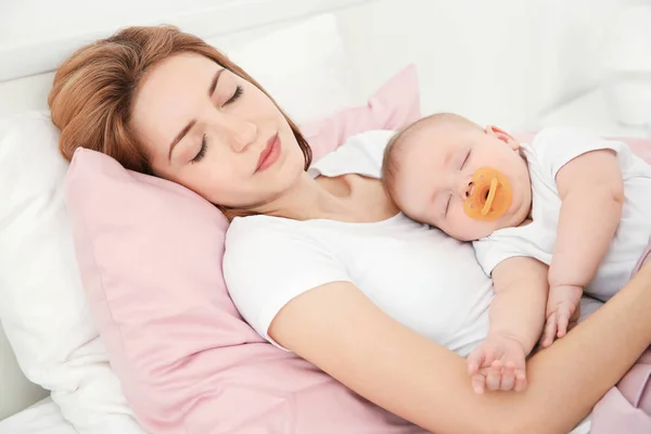 Young woman with cute baby sleeping on bed at home — Stock Photo, Image