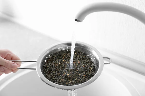 Ruwe linzen met leidingwater wassen vóór het koken in de keuken — Stockfoto