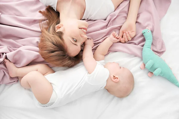 Young woman with cute sleeping baby lying on bed at home — Stock Photo, Image