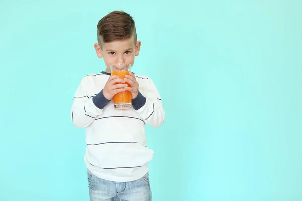 Mignon petit garçon boire du jus sur fond de couleur — Photo