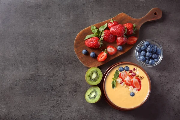 Чаша свіжого йогурту з фруктами на гранжевому фоні — стокове фото