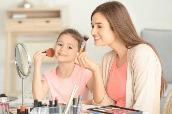 Mujer e hija pequeña aplicando maquillaje —  Fotos de Stock